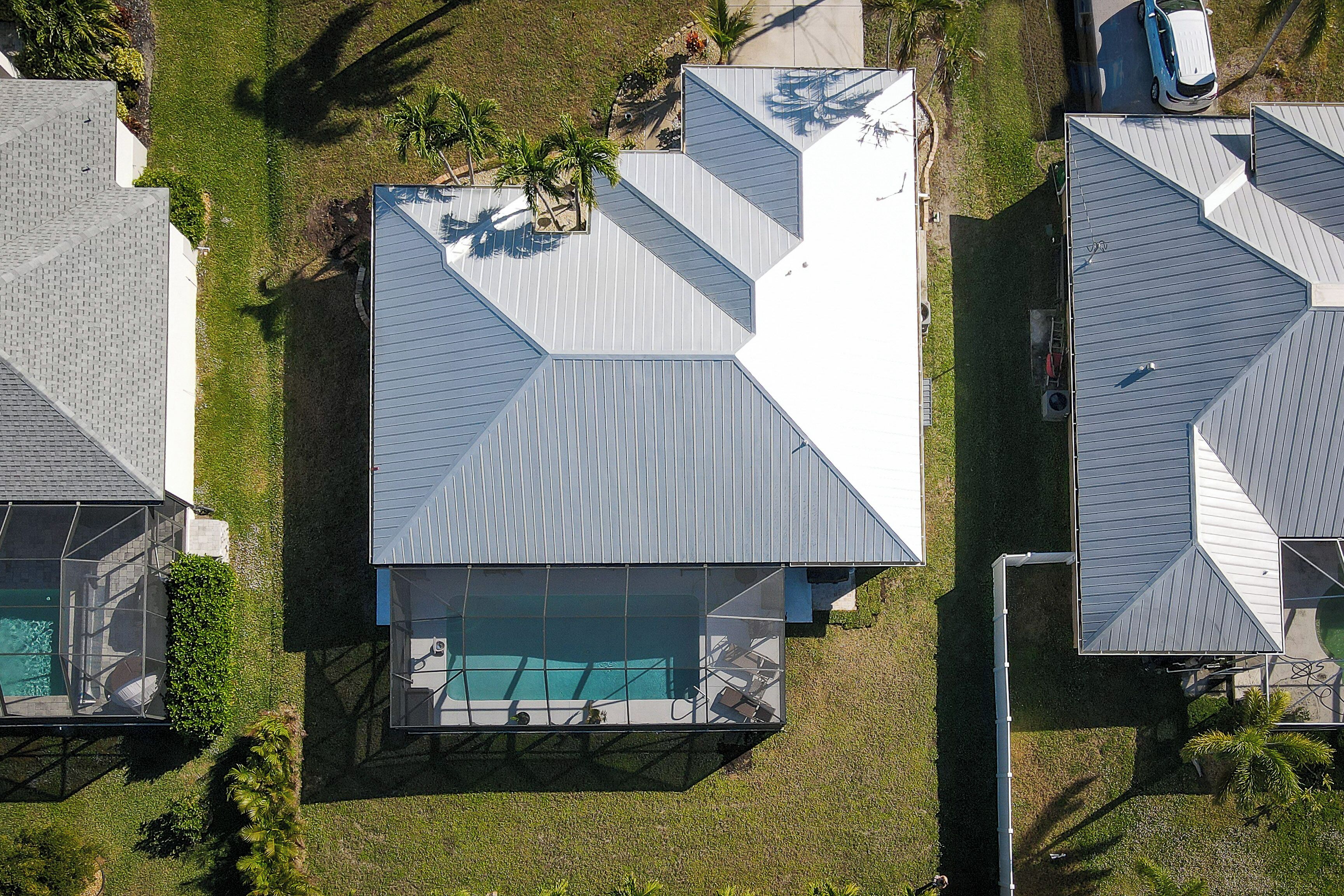 A modern house with a large swimming pool, a covered patio, and a well-maintained lawn.