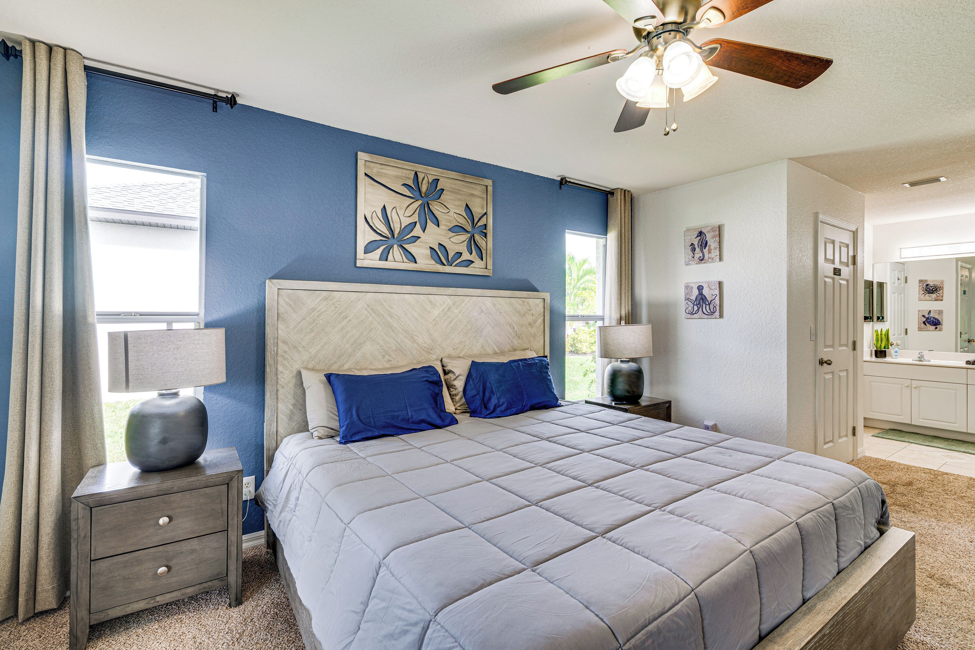 A bedroom with a bed, nightstand, ceiling fan, and artwork on the wall.