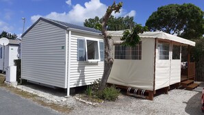 A small, single-story mobile home with a white exterior and a small porch area. - Mobile home 3 bedrooms 6 pers on camping cap soleil Oléron (Saint-Denis-d'Oléron)
