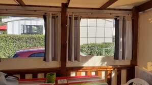A room with a wooden ceiling, a striped table, a green bowl, and a framed picture. - Mobile home 3 bedrooms 6 pers on camping cap soleil Oléron (Saint-Denis-d'Oléron)