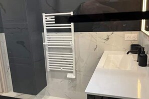 Ein Badezimmer mit einem weißen Waschbecken, einem Handtuchhalter und einer Marmor-Spritzschutzwand.
