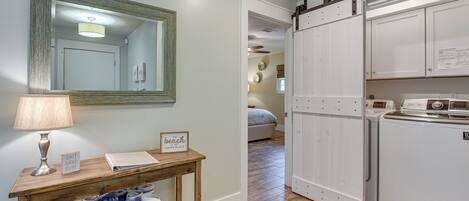A laundry area with a wooden table, a lamp, and a basket of towels.