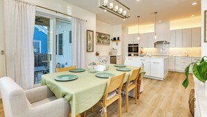 Une cuisine moderne avec des meubles blancs, un îlot central et un coin repas avec une table dressée pour quatre personnes.