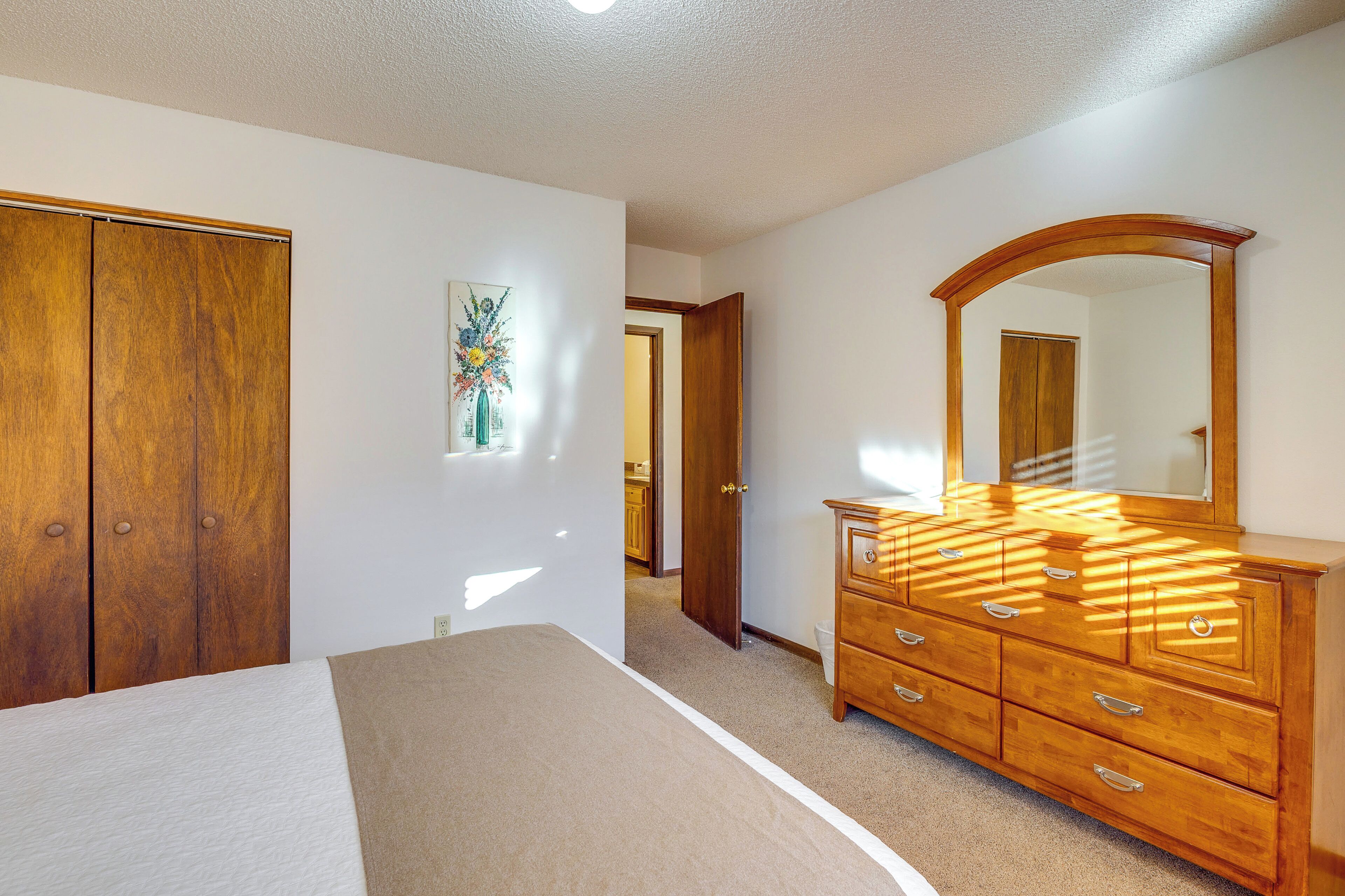 Une chambre à coucher avec une commode en bois, un lit et un grand miroir.