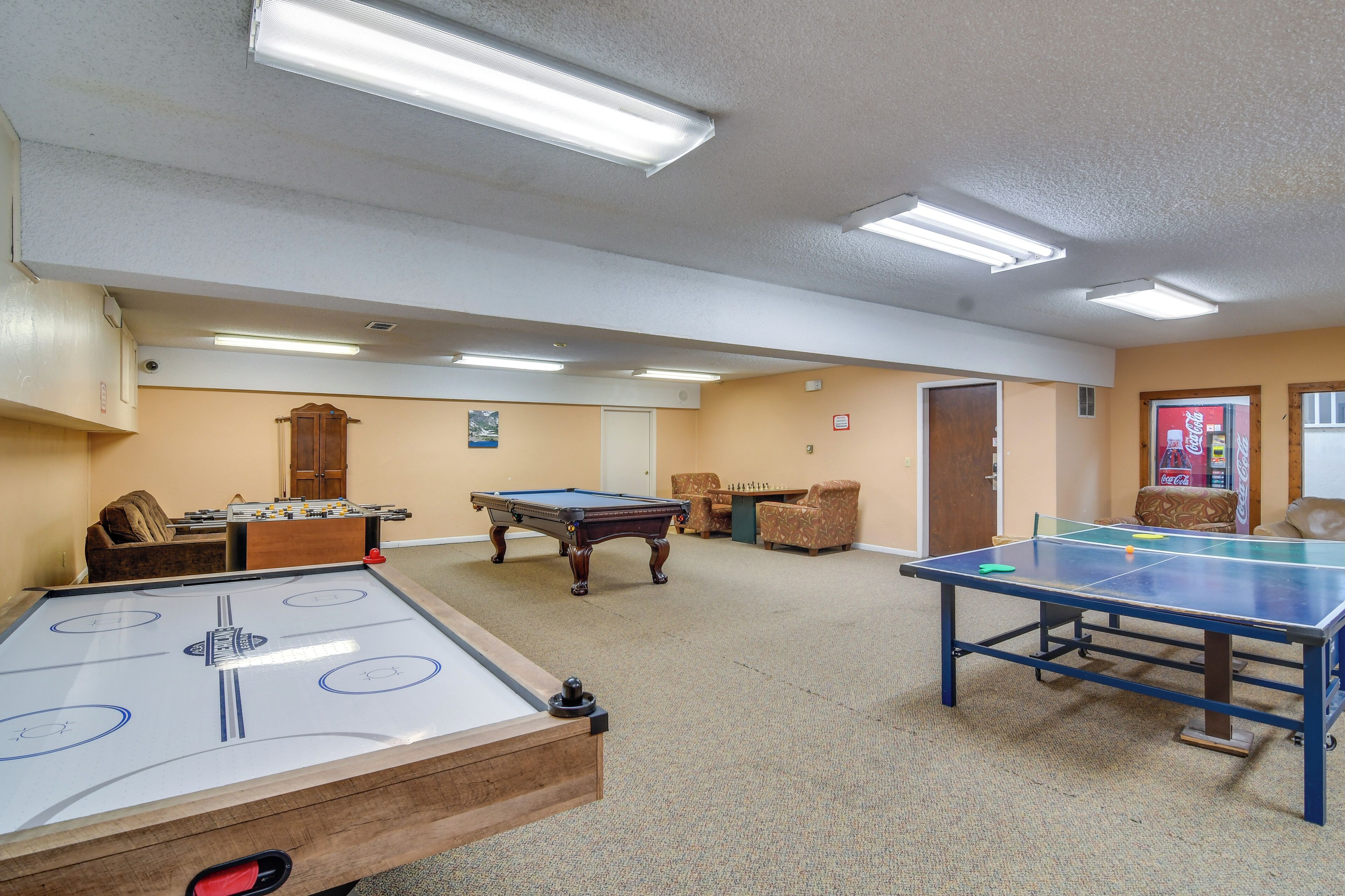 Una sala recreativa con mesa de futbolín, mesa de billar y mesa de ping pong.