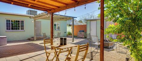 An outdoor patio area with wooden tables and chairs, a covered seating area, and a view of a residential neighborhood.