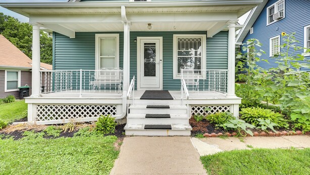 A two-story house with a front porch, a door, and steps leading to the entrance. - Walk to Nightlife District! Omaha Benson Bungalow (Omaha)