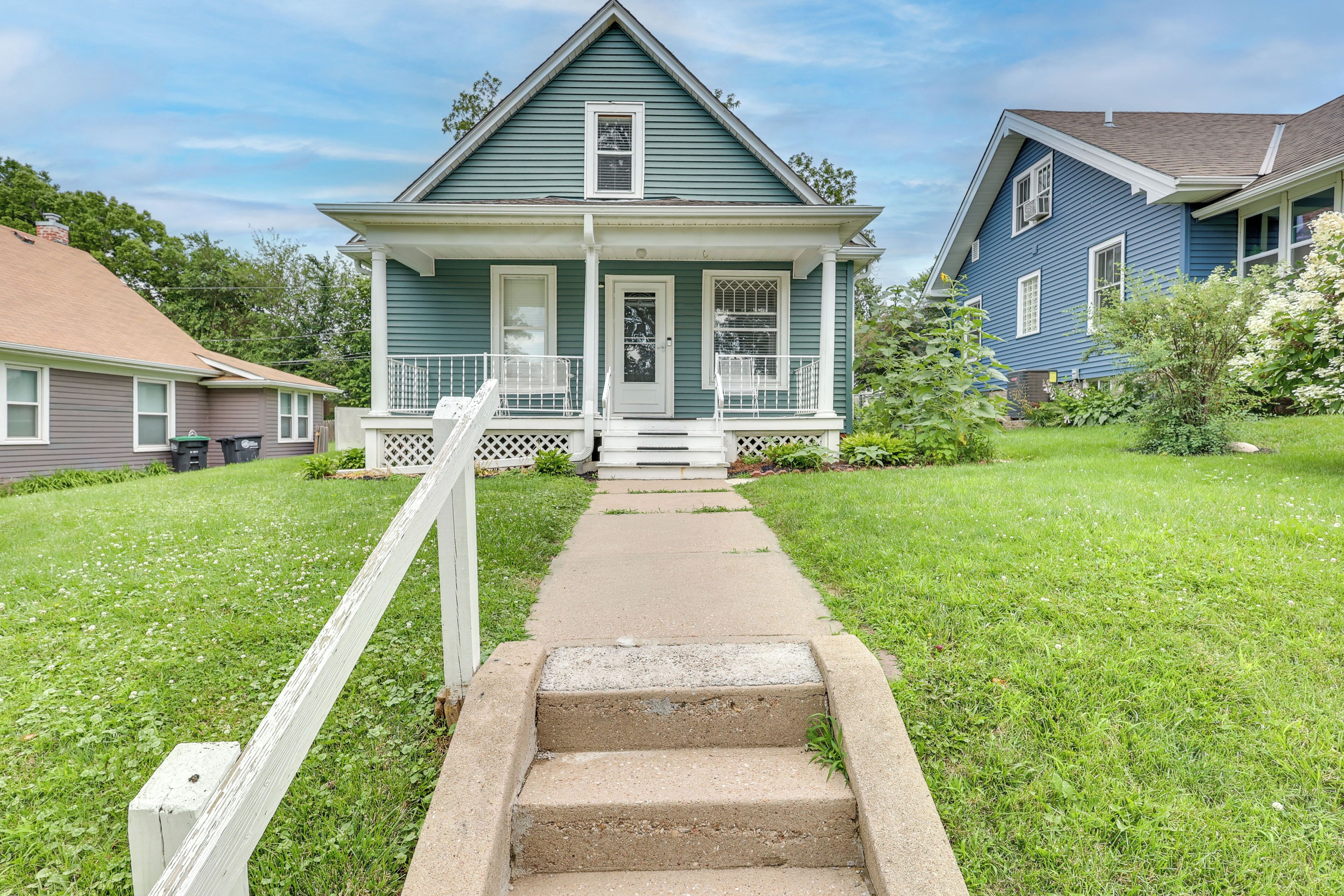A two-story house with a front porch, a pathway leading to the door, and a small front yard.