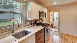A modern kitchen with a stainless steel sink, a built-in oven, and a microwave. - Walk to Nightlife District! Omaha Benson Bungalow (Omaha)