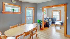A living room with a wooden dining table, chairs, a sofa, and a potted plant. - Walk to Nightlife District! Omaha Benson Bungalow (Omaha)