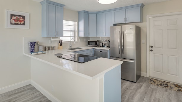 A modern kitchen with light blue cabinets, a stainless steel refrigerator, and a white countertop. - Walk to Shops & Eats, 3 Mi to Beach! Hollywood Gem (Hollywood)
