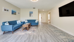 A living room with a sectional sofa, a coffee table, and a flat-screen TV mounted on the wall. - Walk to Shops & Eats, 3 Mi to Beach! Hollywood Gem (Hollywood)
