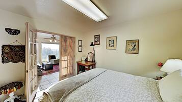 A bedroom with a large bed, a desk, a chair, and a window with a view.