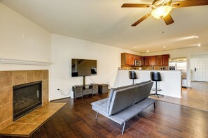 Uma sala de estar moderna com lareira, sofá, televisão e ventilador de teto.