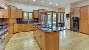 A modern kitchen with wooden cabinets, a granite countertop, stainless steel appliances, and a large island. - Scenic Lagrange Retreat! 3,600 Sq Ft, Pool Access (LaGrange)