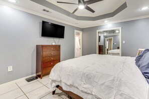 A bedroom with a bed, a wooden dresser, a TV mounted on the wall, and a ceiling fan. - Dallas Area Home w/ Hot Tub, Families Welcome! (Duncanville)