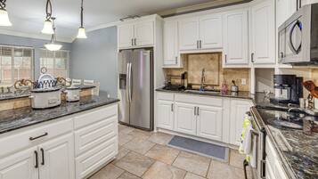 A modern kitchen with white cabinets, stainless steel appliances, and granite countertops.
