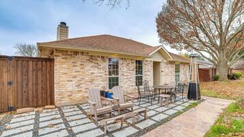 A brick house with a patio area featuring outdoor furniture and a stone pathway.