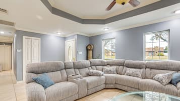 A living room with a sectional sofa, a glass coffee table, and a large window with a view.