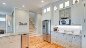 A modern kitchen with white cabinetry, stainless steel appliances, and a wooden floor.