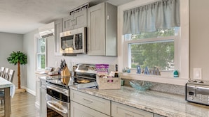A kitchen with a built-in oven, microwave, and toaster, a window with a view of trees, and a 'Welcome' sign above the cabinets. - Coastal York Gem Near Beach: Work, Play & Explore! (York Beach)
