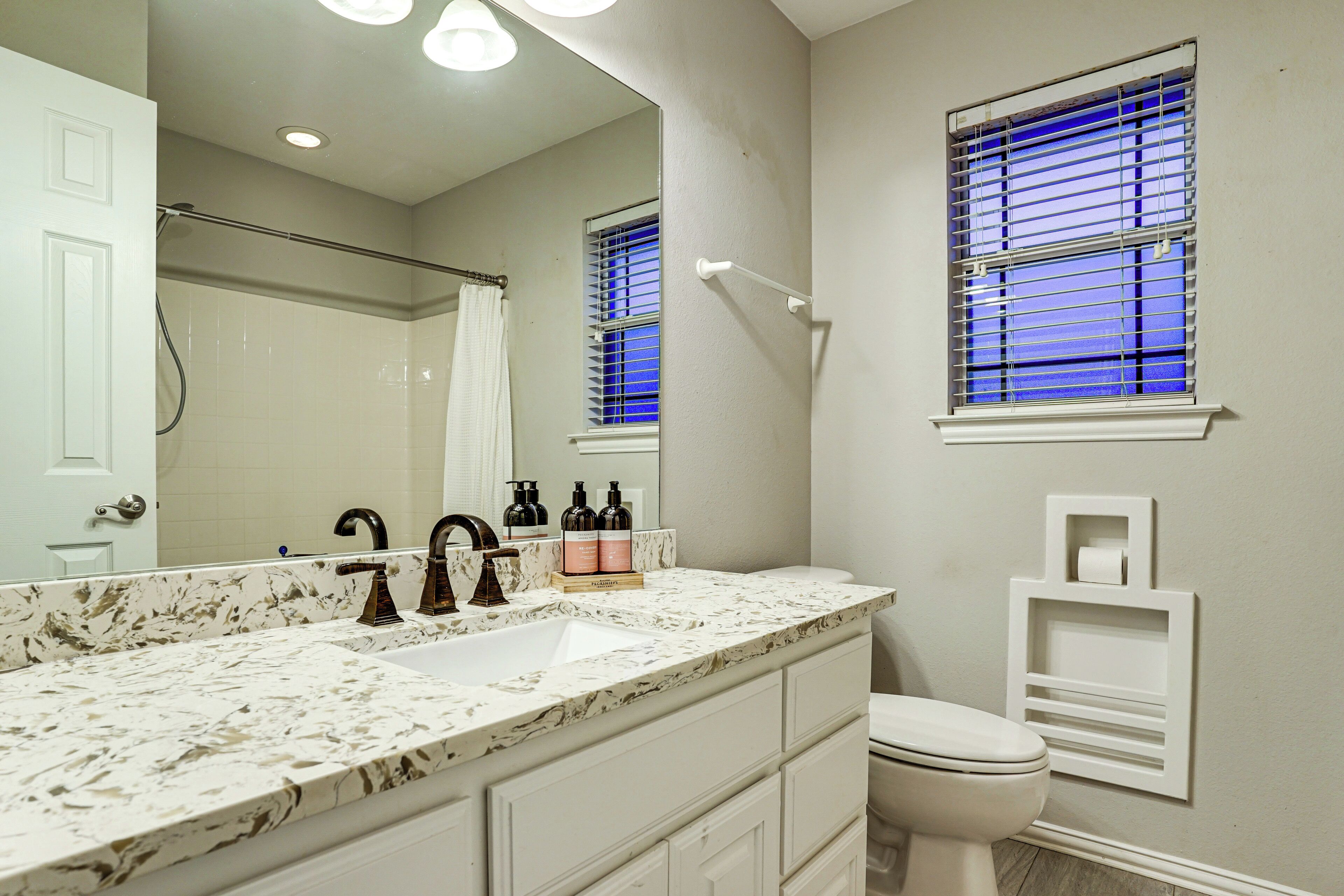 A bathroom with a marble sink, a toilet, and a shower.