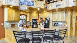A spacious kitchen with wooden cabinets, a central island with bar stools, and a stone backsplash. - Big Pine Lake Home w/ Dock & Game Room in Aitkin (Aitkin)
