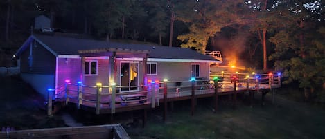 A house with a porch, deck, and a small outdoor area with a fire pit.