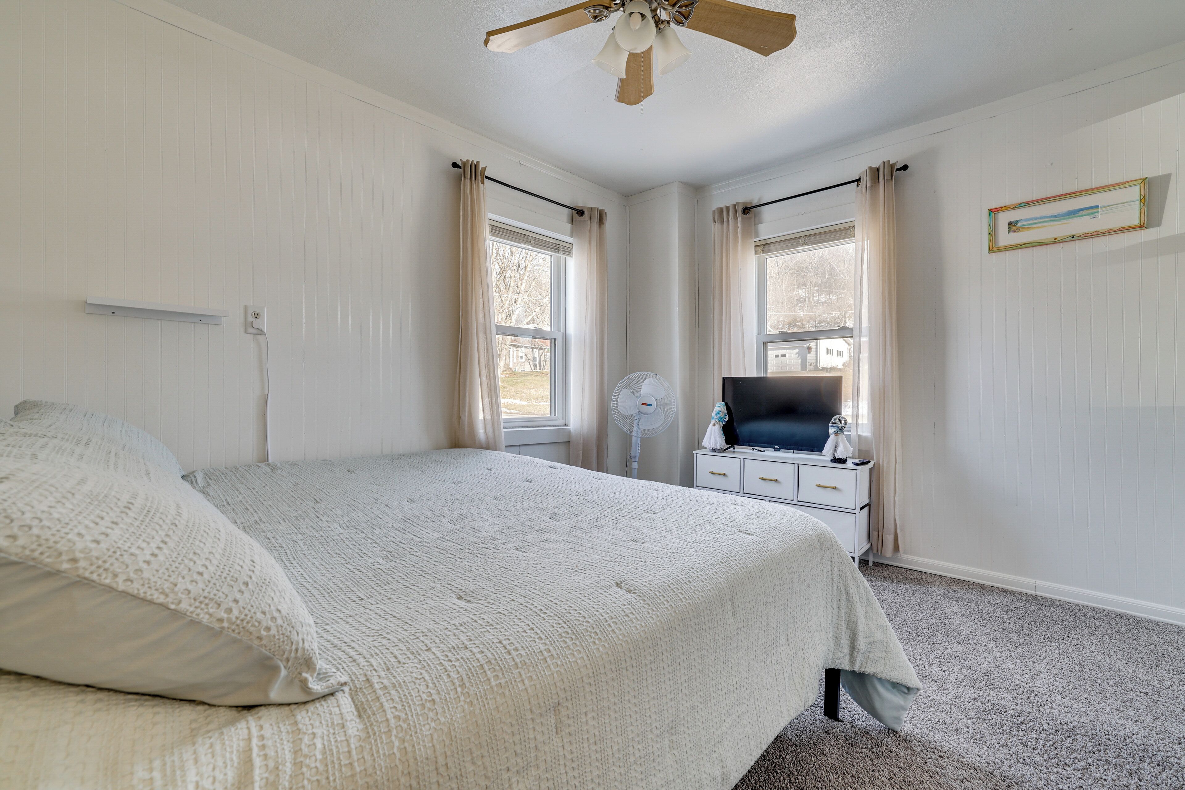 Une chambre à coucher avec un lit, une table de chevet, un téléviseur et un ventilateur de plafond.