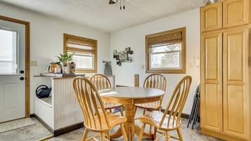 A dining area with a round wooden table and four chairs, a ceiling fan, and wooden cabinets.