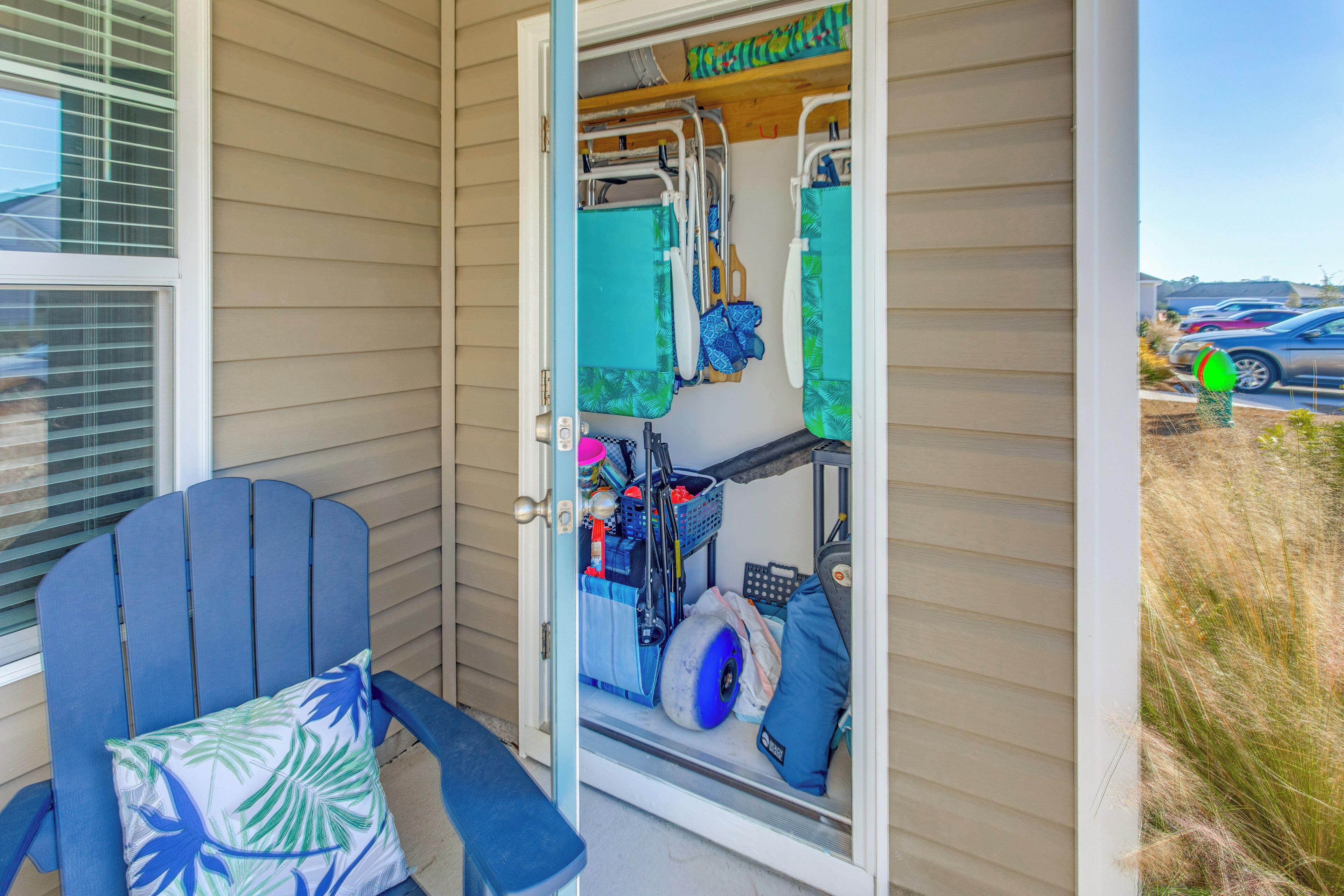 A room with a blue chair, a small table, and a door leading to a storage area with a cart and various items.
