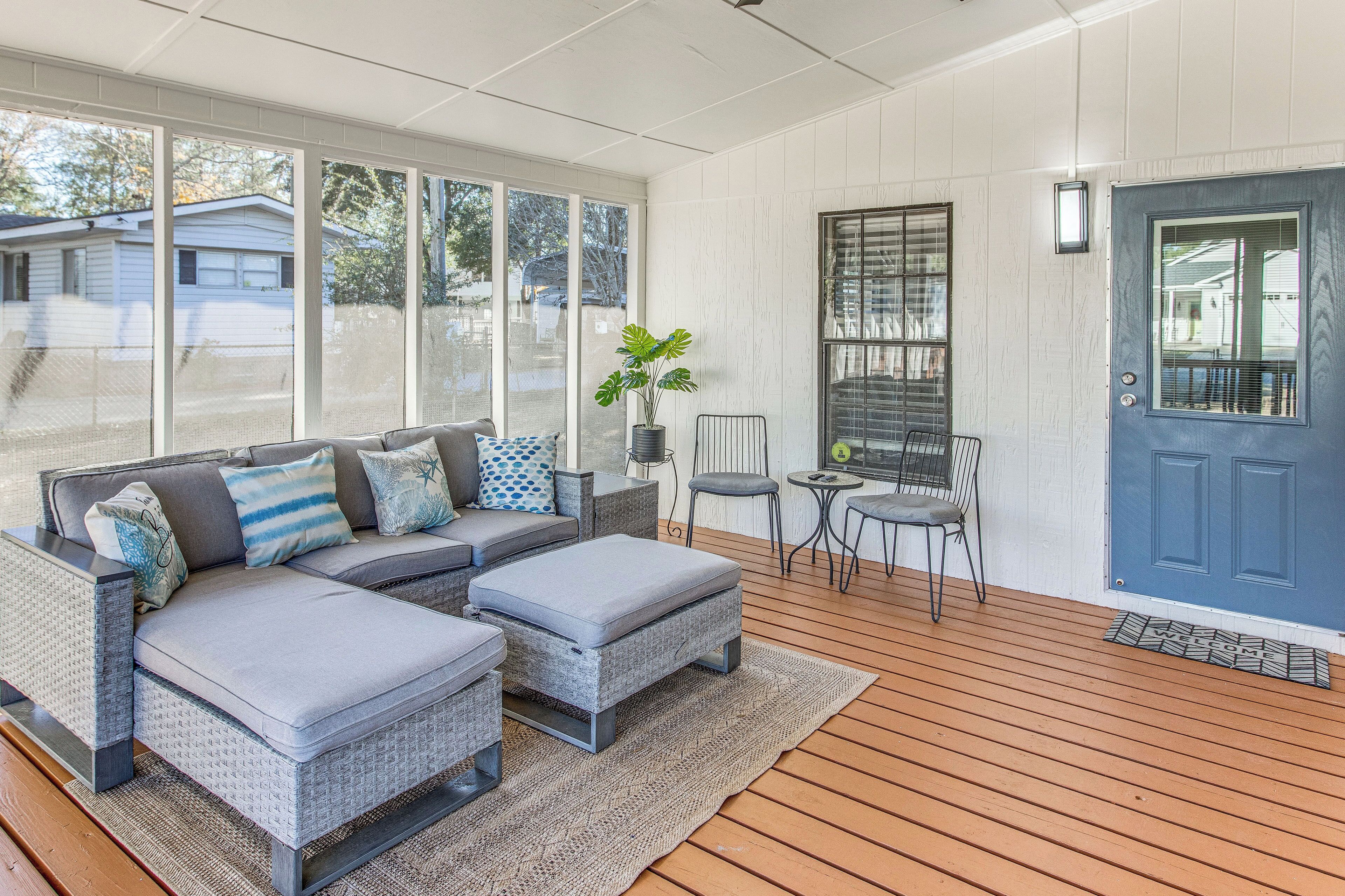 A sunroom with a grey sectional sofa, a small table, and a chair.