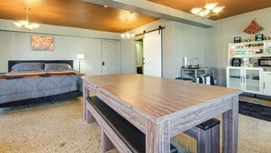 A bedroom with a bed, a wooden table, a bench, a kitchenette, and a door leading to another room. - Unique Studio in Downtown Lebanon, Pets Welcome! (Lebanon)