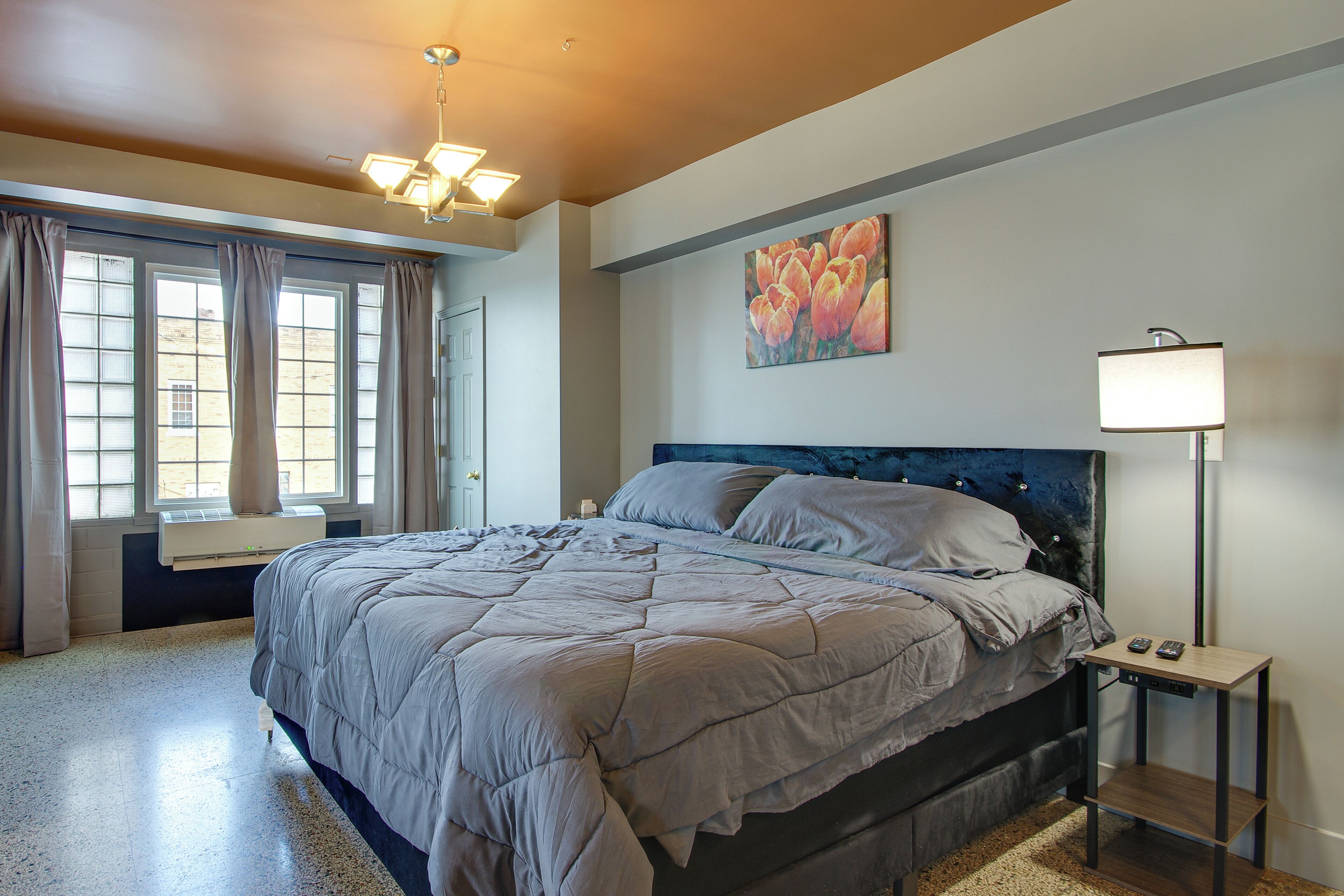 A bedroom with a bed, a nightstand, a lamp, and a window with curtains.