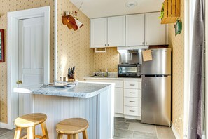 A kitchen with a marble island, wooden stools, stainless steel appliances, and patterned wallpaper. - Outdoorsy Delphi Retreat w/ Fishing Pond + Trails (Delphi)