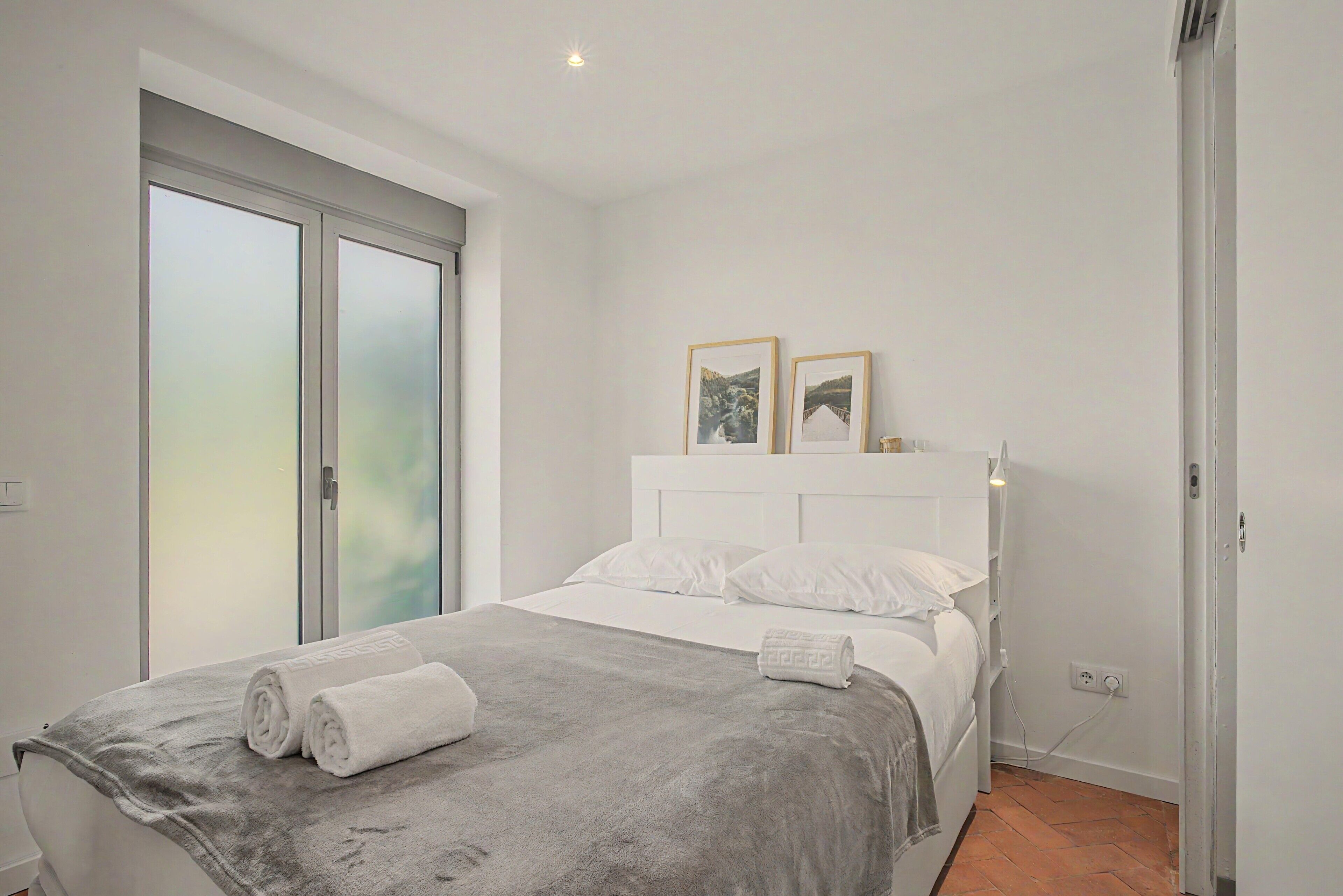 Ein Schlafzimmer mit Bett, Fenster und Tür.