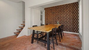 A dining area with a wooden table and chairs, a staircase, and a wall with circular cutouts. - Cantinho dos Avós – Country House with Mountain View, Wi-Fi and Air Conditioning (Sever do Vouga)