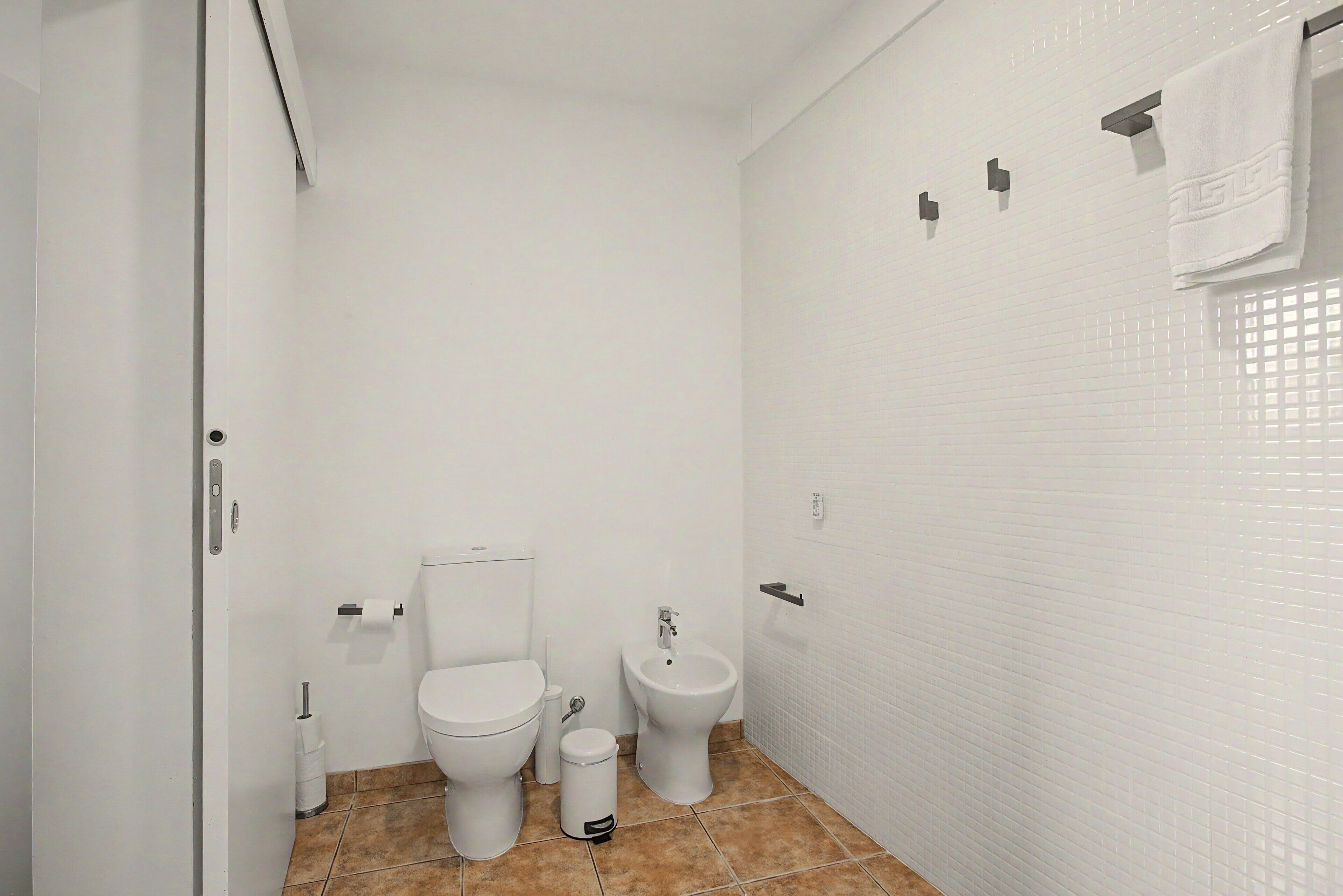 Un baño con inodoro, bidé y un cubo de basura.