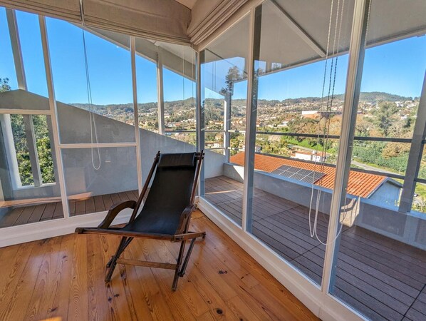 A balcony with a wooden floor and a black lounge chair.