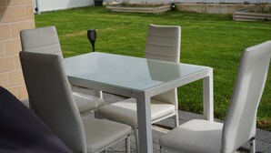 Eine Terrasse mit einem Glastisch und vier weißen Stühlen.