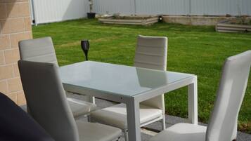 A patio with a glass-top table and four white chairs.