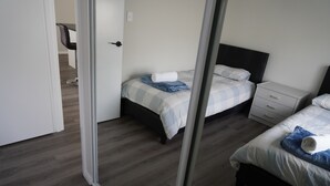Ein Hotelzimmer mit zwei Betten, einem Schreibtisch und einem Stuhl.