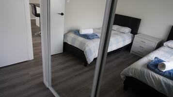 A hotel room with two beds, a desk, and a chair.