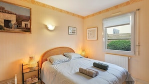 Une chambre à coucher avec un lit, des lampes de chevet, une fenêtre donnant sur un beau paysage et un tableau accroché au mur.