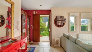 Un couloir avec un meuble rouge, un canapé blanc et une bibliothèque.