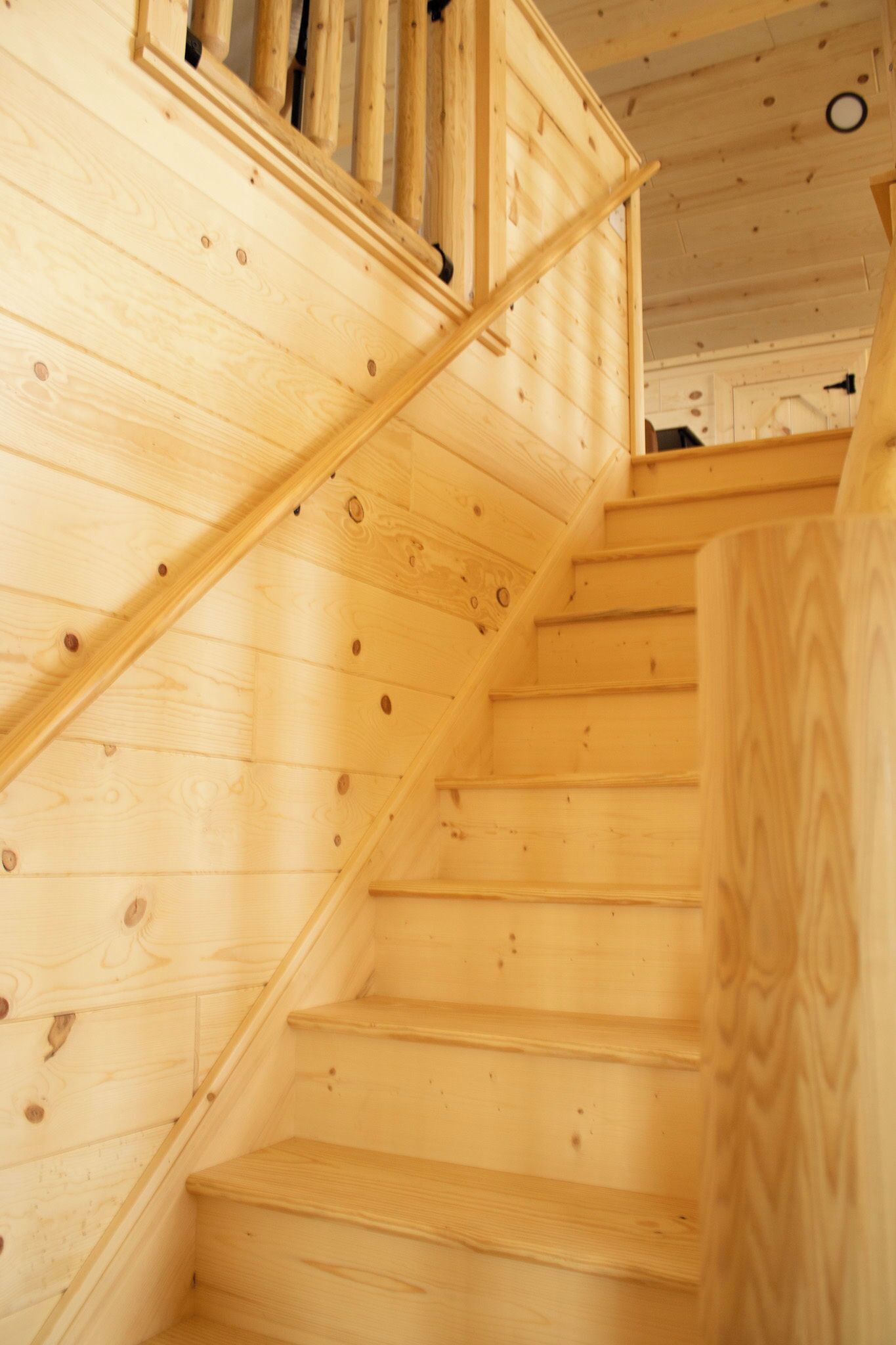 A wooden staircase with a handrail and a landing area.
