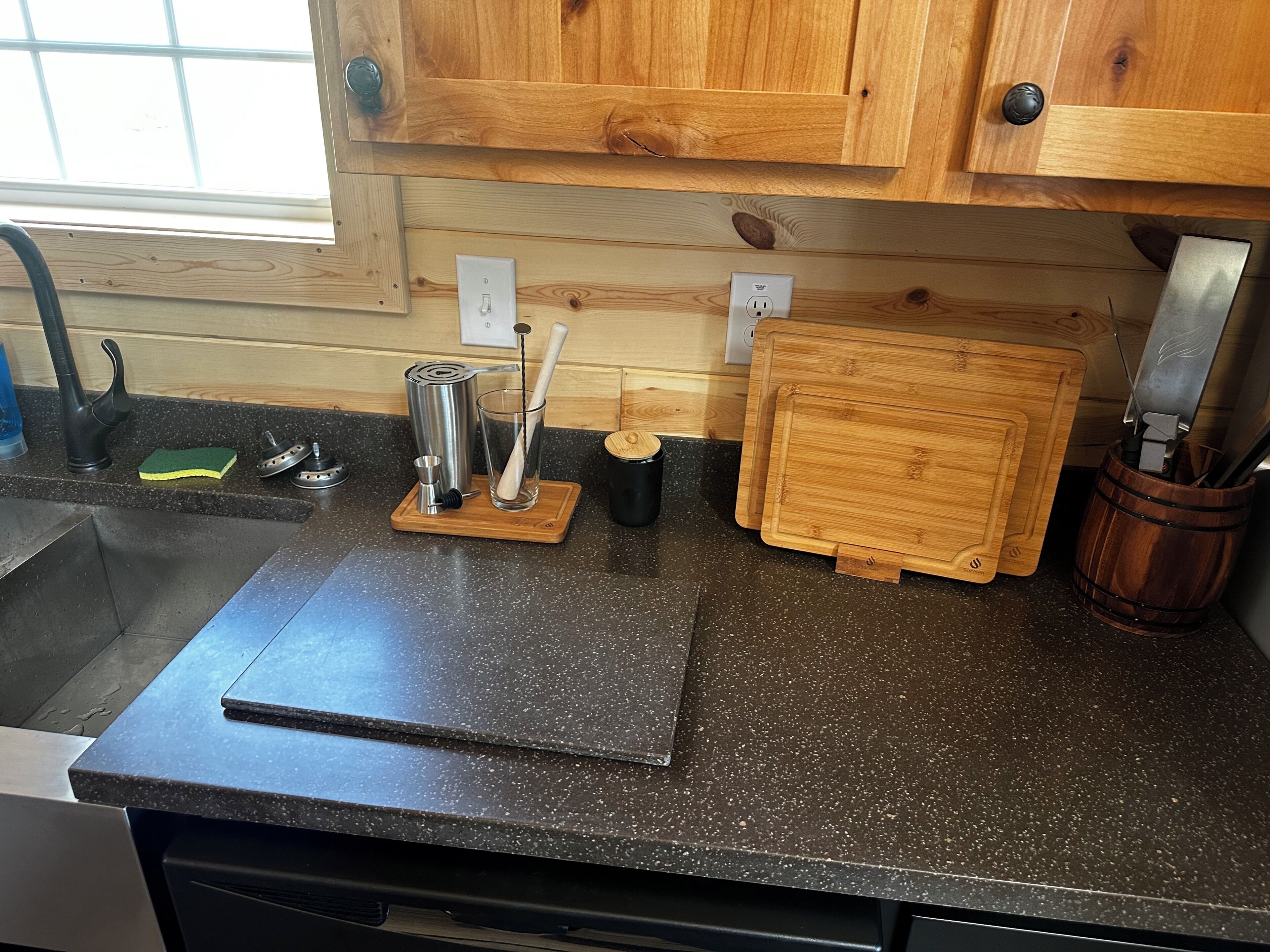 Un piano di lavoro in cucina con un lavandino, un tagliere, un portacoltelli e una macchina da caffè.