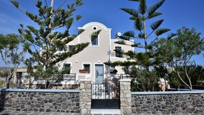 Ein Gebäude im mediterranen Stil mit einer Stein-Fassade, einem zentralen Rundbogenfenster und einem Balkon.