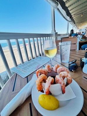 Taula de menjador amb un plat de gambes, un got de vi blanc i una llesca de llimona.