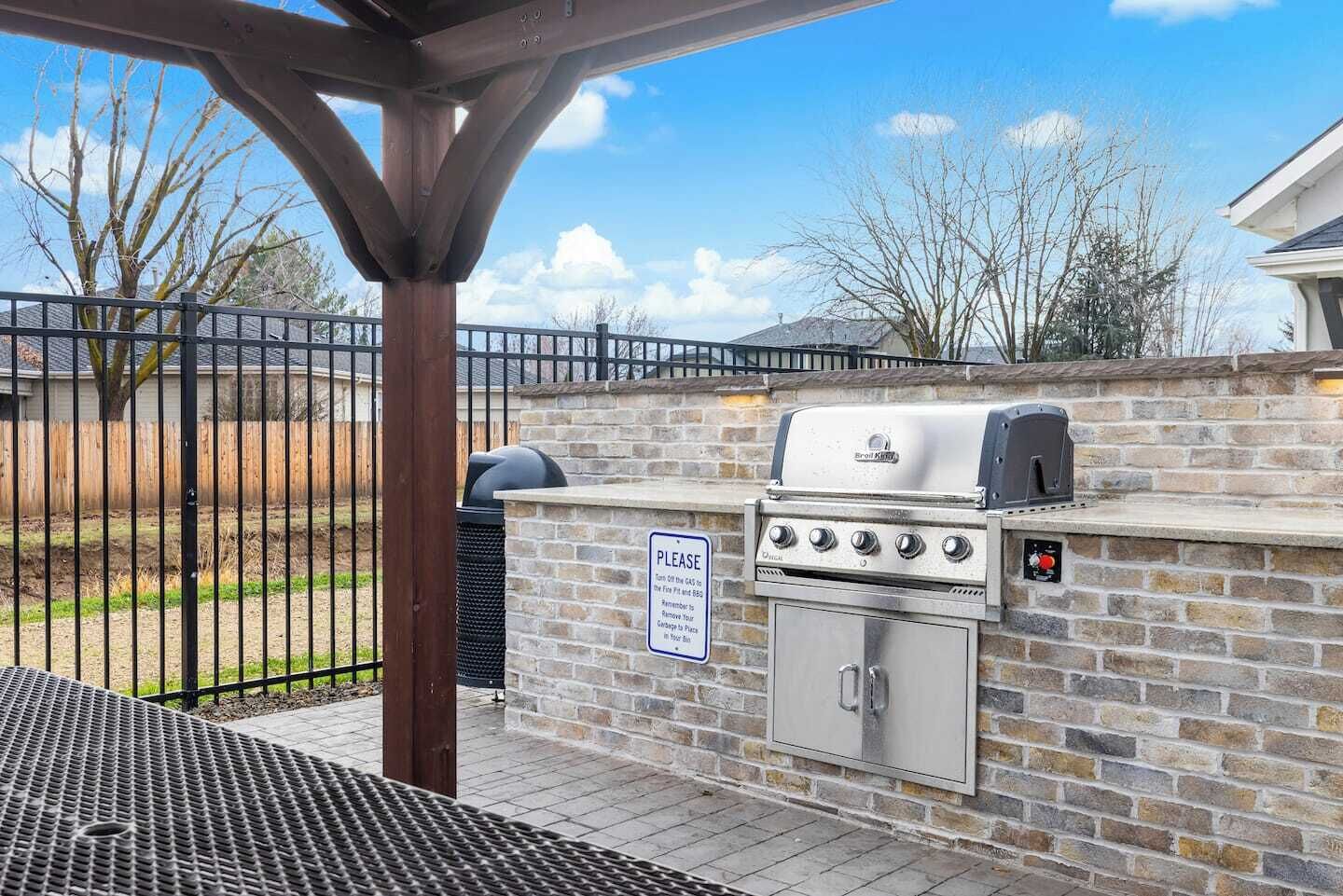 Ein Grillbereich im Freien mit einer Steinsäule und einem Metallgrill.